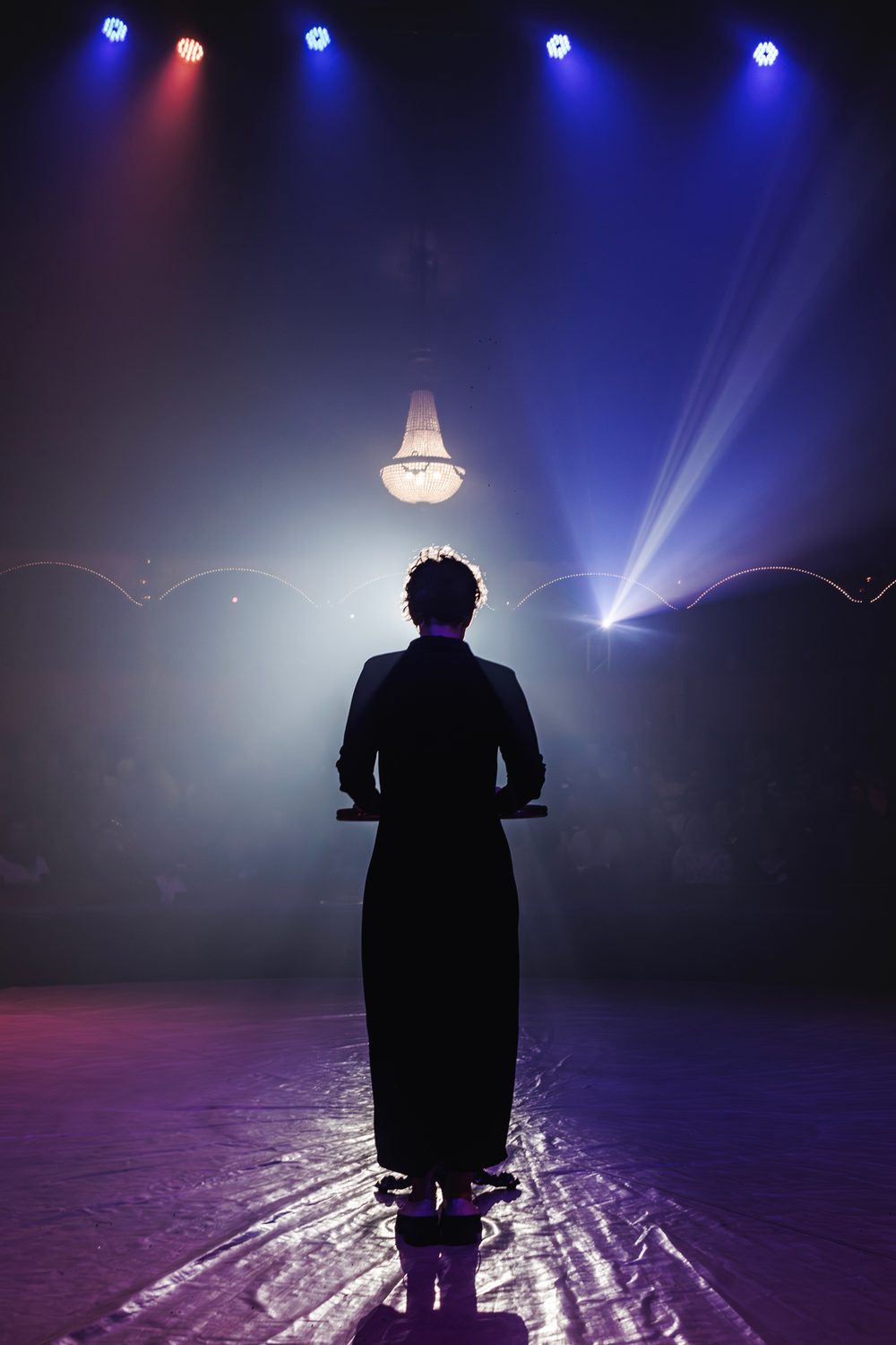Hélène de dos sur scène, face à une salle pleine, lors d'une Journée du Village