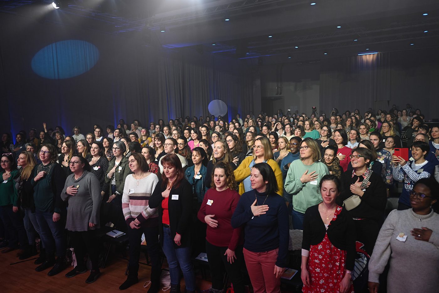 Une salle entière de Villageoises, la main sur le cœur