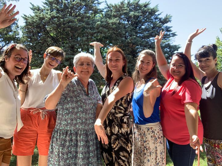 Huit Villageoises dans un jardin, bras levés, pendant une Fête des Voisines