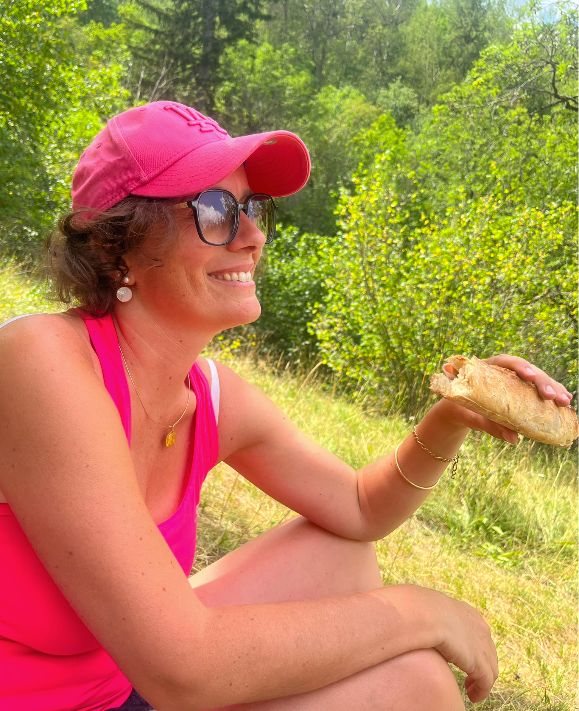 Une Villageoise en casquette, un sandwich à la main, assise dans l'herbe
