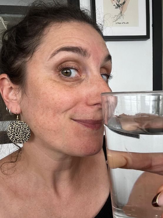 Une Villageoise lève son verre d'eau vers l'objectif