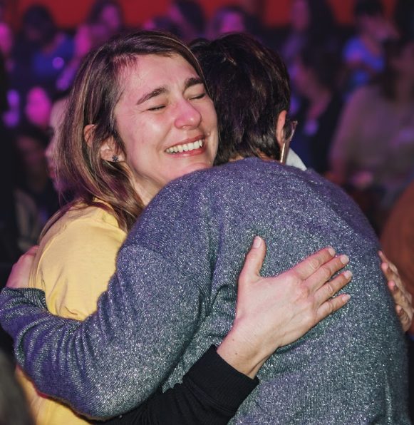 Deux Villageoises qui s'enlacent, les yeux fermés, en pleine salle